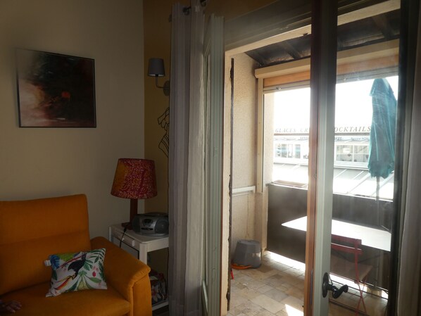 Une pièce avec un canapé, une lampe, un tableau et une vue sur l’extérieur.