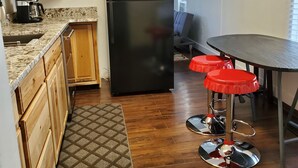 Una cucina compatta con mobili in legno, un frigorifero nero e una macchina da caffè.
