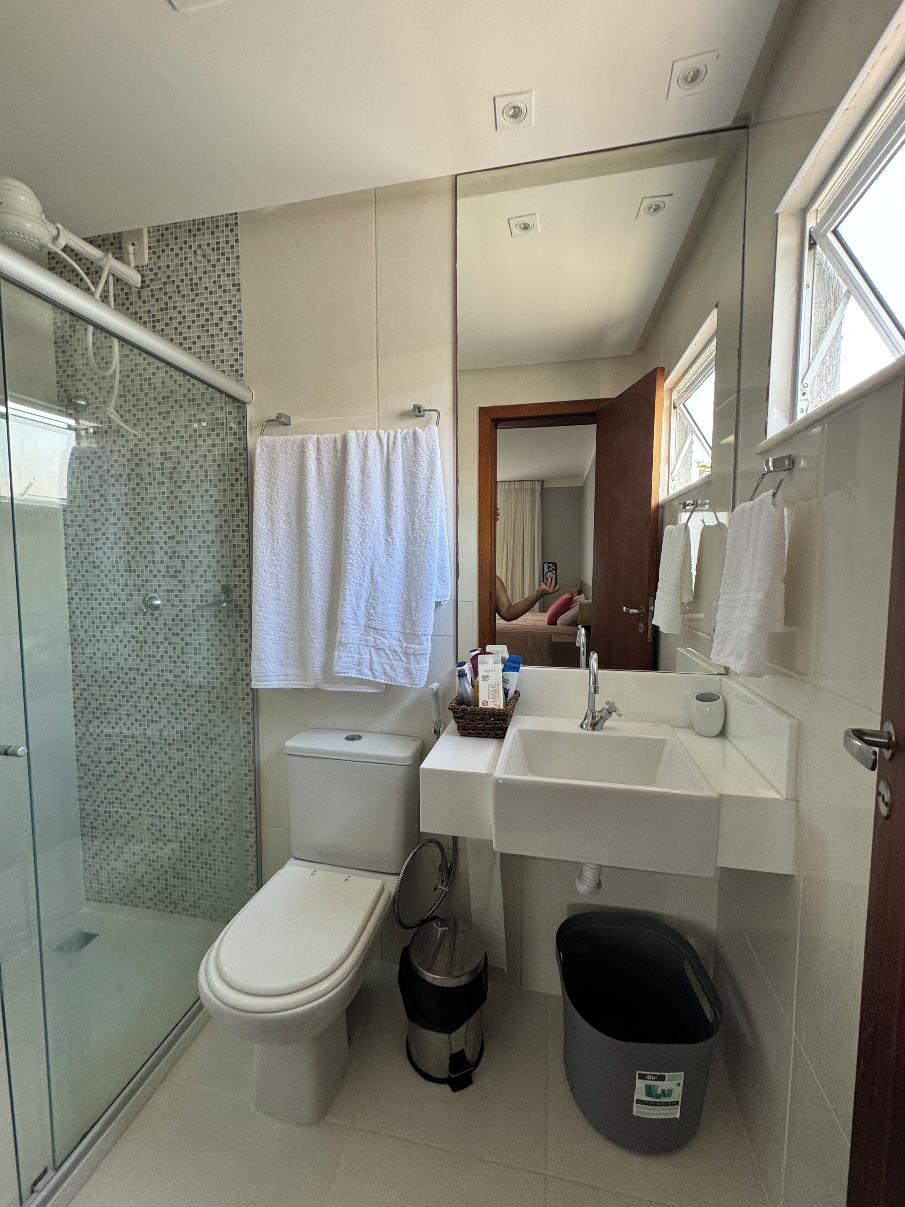 Un baño moderno con cabina de ducha de vidrio, inodoro, lavabo y espejo.