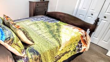 Un dormitorio con cama, cómoda, televisor en la pared y una puerta.