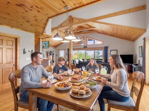 Een houten eettafel met eten, een televisie en een plafond met houten balken.