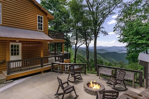 Une cabane en rondins avec une terrasse, un espace salon extérieur et un foyer.