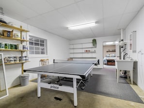 A room with a ping pong table, shelves with various items, a window, and a door leading to another room. - September Special | Hot Tub+Breathtaking Mtn Views (Spruce Pine)
