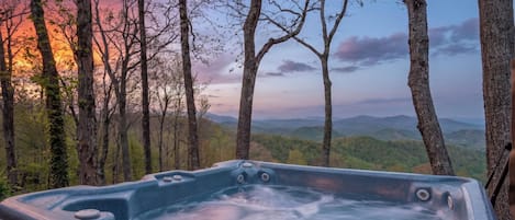 A hot tub in a forest with a view of mountains.