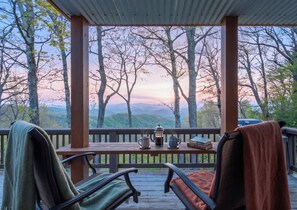 A covered outdoor seating area with chairs and a table, overlooking a forested landscape. - September Special | Hot Tub+Breathtaking Mtn Views (Spruce Pine)