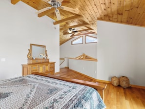 A bedroom with a wooden ceiling, a bed with a patterned bedspread, a dresser with a mirror, and a skylight. - September Special | Hot Tub+Breathtaking Mtn Views (Spruce Pine)