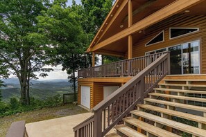 A wooden cabin with a balcony and a staircase leading to a garage. - September Special | Hot Tub+Breathtaking Mtn Views (Spruce Pine)