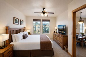Ein Hotelzimmer mit einem Bett, einem Fernseher, einem Deckenventilator und einem Essbereich mit Tisch und Stühlen.