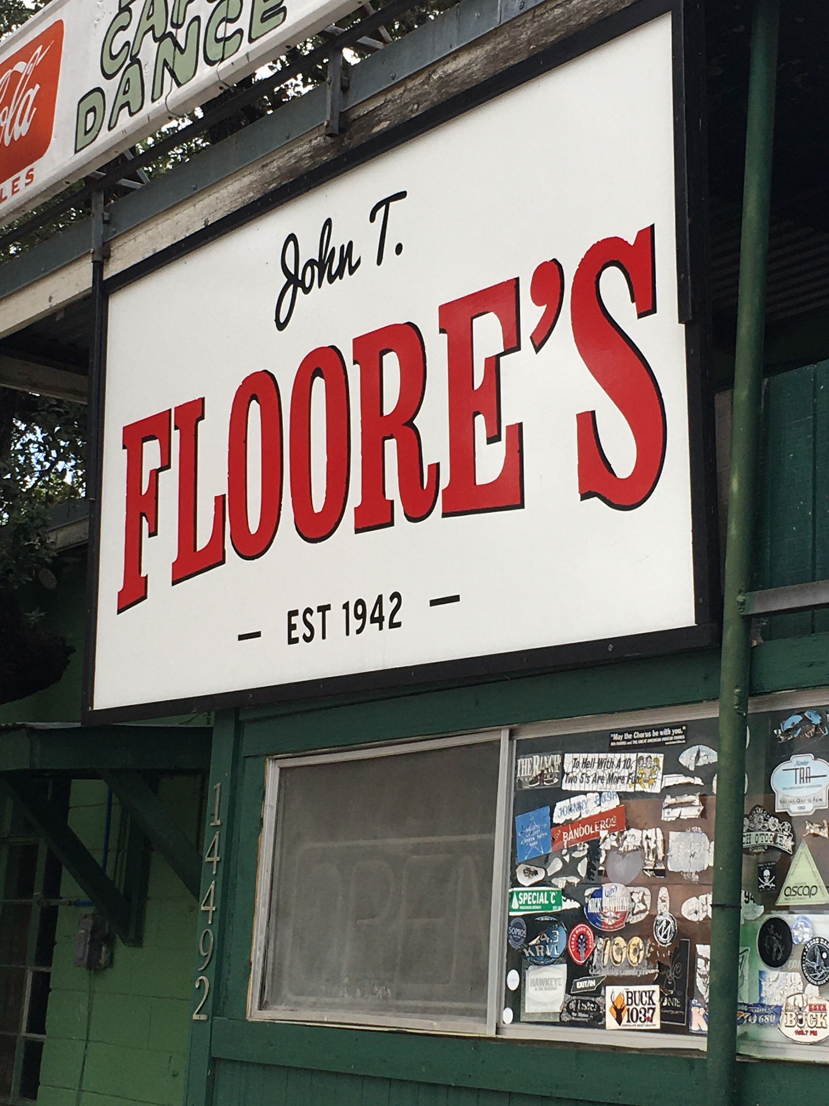 Un edificio con un cartel llamativo que dice "John T. FLOORE'S EST 1942".