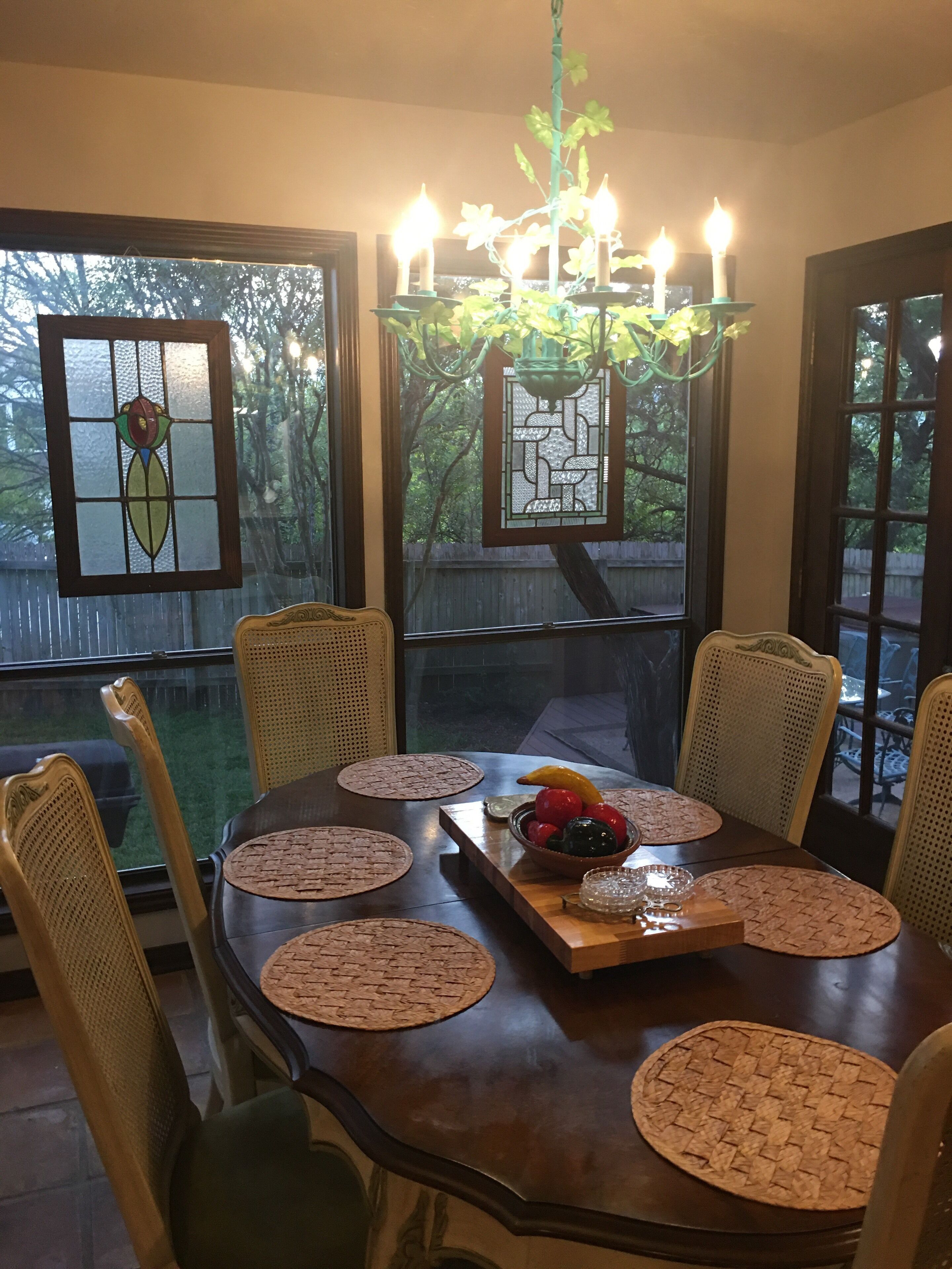 A dining area with a wooden table, woven chairs, and a chandelier.