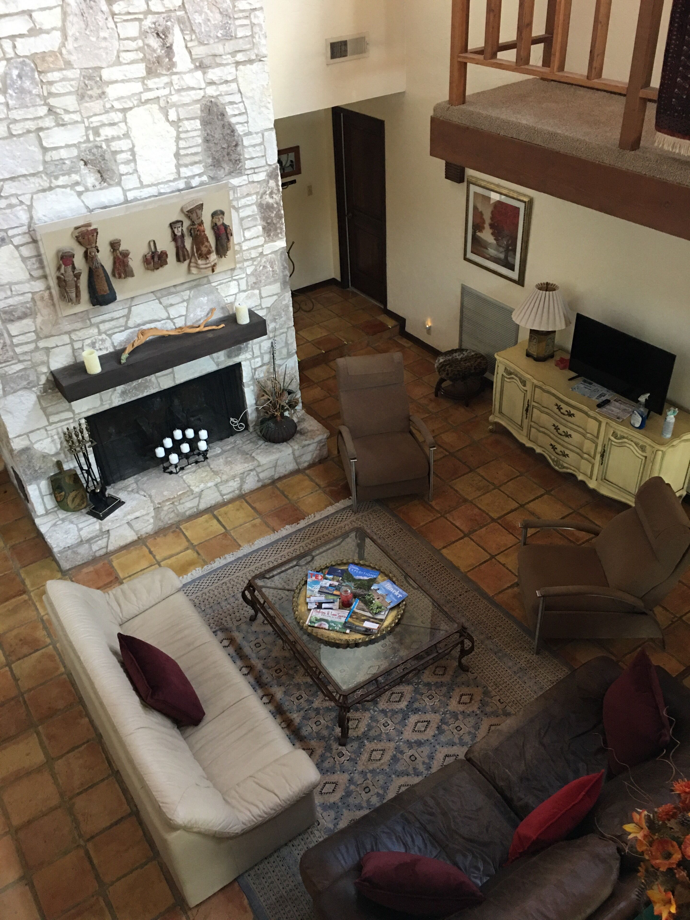 A living room with a stone fireplace, a glass coffee table, and a sofa.