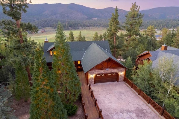 A cabin with a garage, surrounded by trees and mountains.