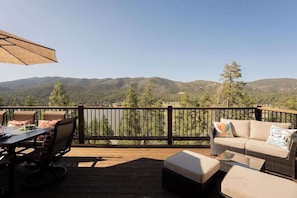 A deck with a table and chairs, a sofa, and an umbrella.