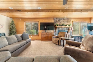 A cozy living room with a sofa, armchair, and a stone fireplace.
