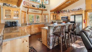 A cabin-style kitchen with wooden cabinets, a stone island, and a bar area. - Timberline Trail. Views, Hot Tub & Game Room (Big Bear Lake)
