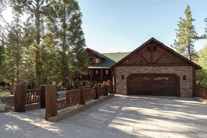 Ein Chalet mit Naturstein-Fassade, einer Holzgarage und einem umzäunten Auffahrtsweg.