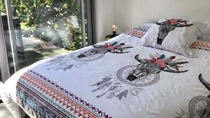 A bedroom with a large bed, a view of greenery outside, and a sliding glass door. - T2 Golf de Valescure, swimming pool, tennis court and private garden  (Saint-Raphaël)