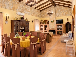 A dining area with a stone wall, a fireplace, and a television.
