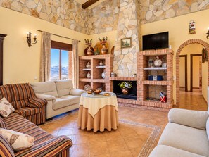 A living room with a stone fireplace, sofas, a round table, and a TV.
