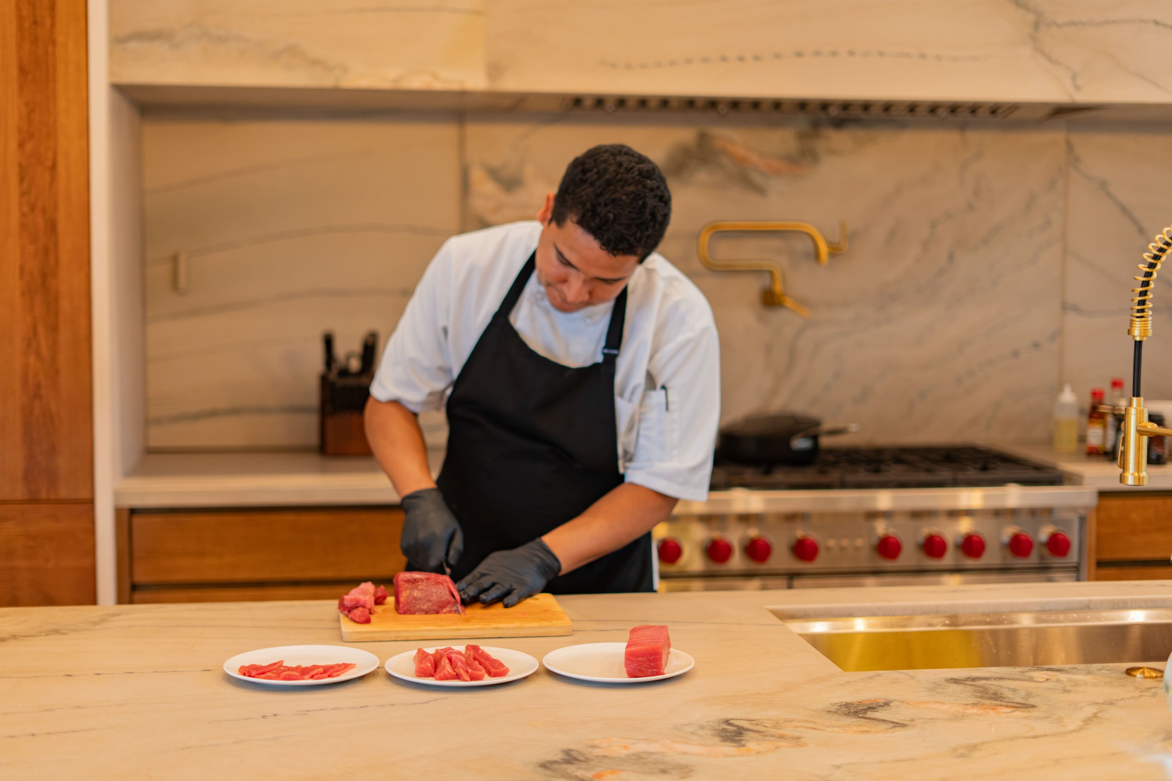 A chef preparing food in a kitchen with marble countertops and a stainless steel stove.