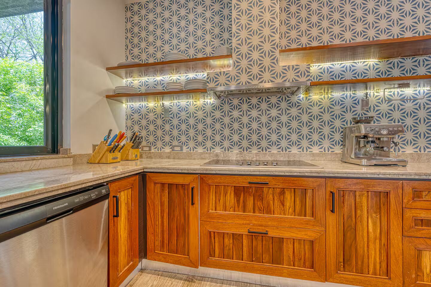 Een keuken met houten kastjes, een inbouwoven en een koffieapparaat.