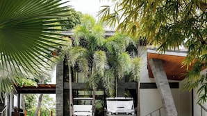 Un edificio moderno con cochera y dos vehículos estacionados debajo.