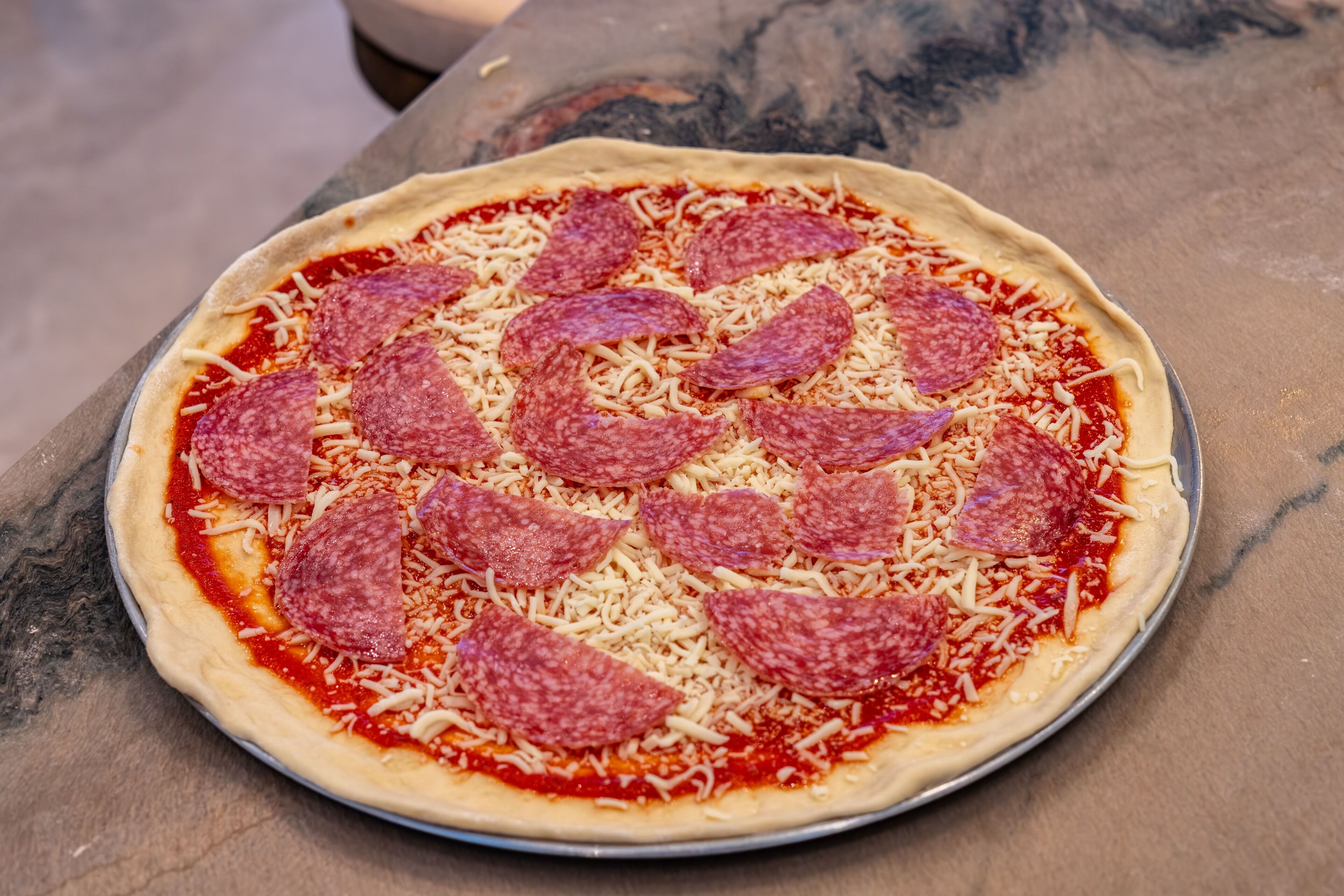A pizza with pepperoni on a metal tray.