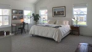 Un dormitorio con una cama grande, un escritorio y dos ventanas.