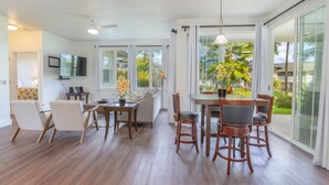 Uma sala de estar ampla com uma mesa de jantar, cadeiras, sofá e televisão.