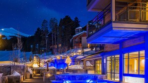 A modern building with a pool area, surrounded by snow-covered landscape and trees.