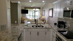 A modern kitchen with white cabinets, a granite countertop, a built-in oven, and a microwave. - Beautifully furnished Condo (Bradenton)