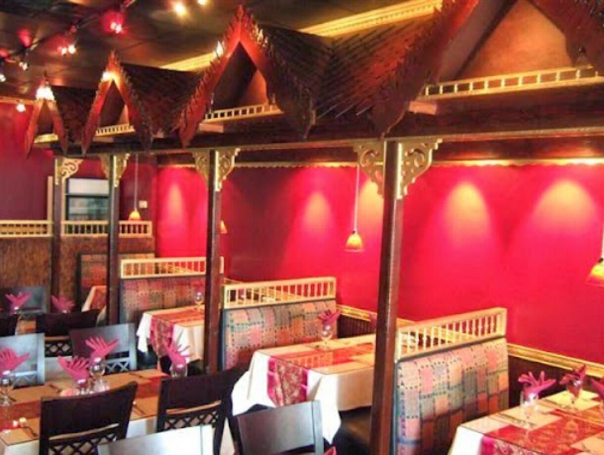 Un ristorante con pareti rosse, arredi in legno e tovaglie decorate.