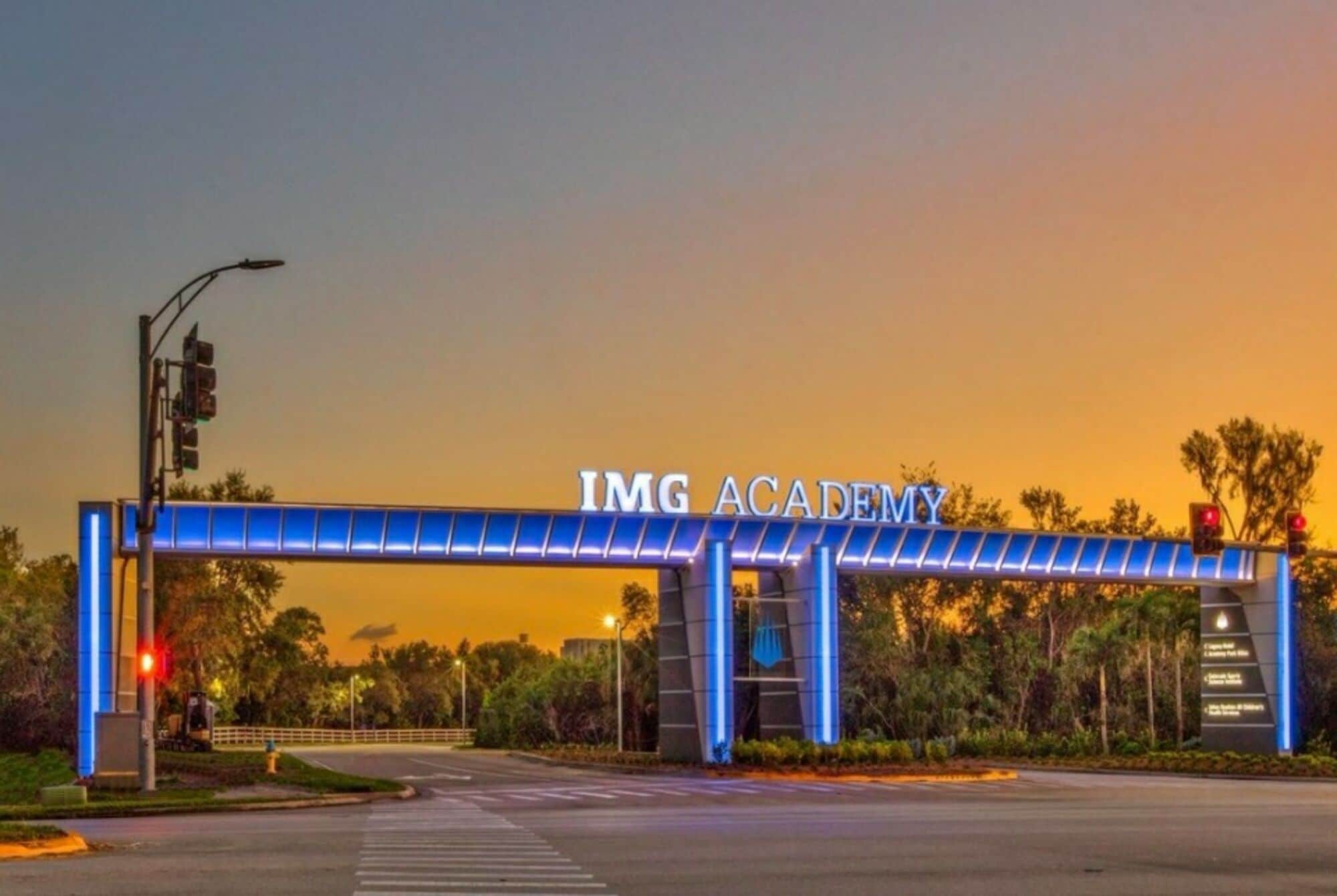 La entrada a IMG Academy, con un arco iluminado en azul y un semáforo.