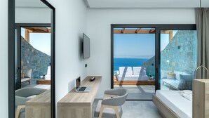 A modern bedroom with a view of the sea, a wooden desk, a laptop, and a comfortable seating area. - Villa Hellena, Minimalist Design & Spa Retreat (Heraklion)