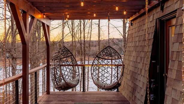 Een houten terras met twee hangstoelen en een houten deur.