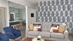 A living room with a grey sofa, blue chairs, a coffee table, and a patterned wallpaper. - Rock House - Lake Views & 15 Mins to Cedar Point (Huron)
