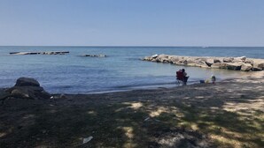 A beach with clear water, rocks, and a person in a red chair. - Rock House - Lake Views & 15 Mins to Cedar Point (Huron)