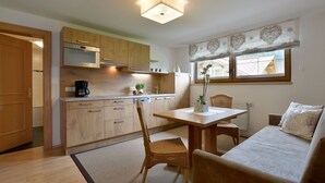 Una cocina compacta con armarios de madera, una mesa de comedor y un sofá.