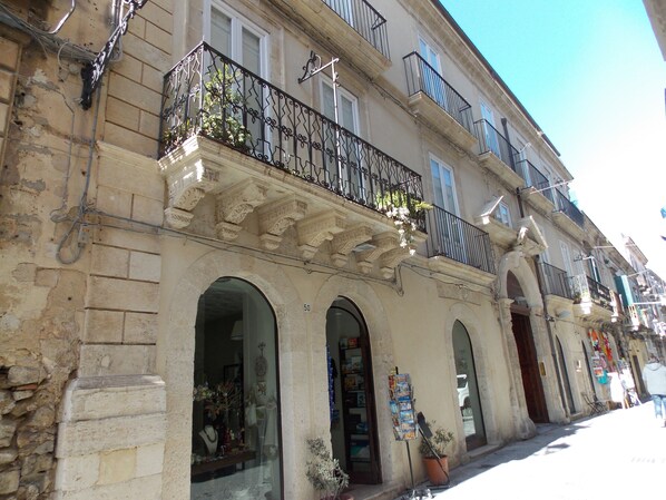 A building with multiple balconies, arched doorways, and a signboard. - B&B Casa D'Alleri Triple Room (Siracusa)