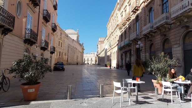 A cobblestone street lined with historic buildings, outdoor seating, and potted plants. - B&B Casa D'Alleri Triple Room (Siracusa)