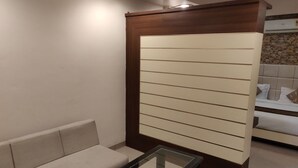 A modern room with a sofa, a glass-top table, and a wooden partition with horizontal lines. - Starlit Select Nirvana (Varanasi)