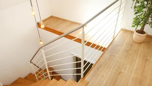 A wooden staircase with a metal railing, a potted plant, and hanging light bulbs. - Amazing home in Nideggen with WiFi (Nideggen)