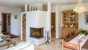 A spacious living room with a fireplace, a dining area with a wooden table and chairs, and a cabinet with glass doors. - Amazing home in Nideggen with WiFi (Nideggen)