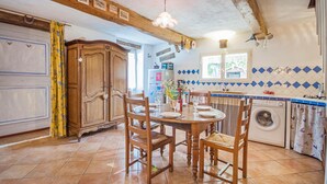 Una cocina con una mesa de comedor dispuesta para cuatro personas, sillas de madera, una lavadora y un salpicadero de azulejos.