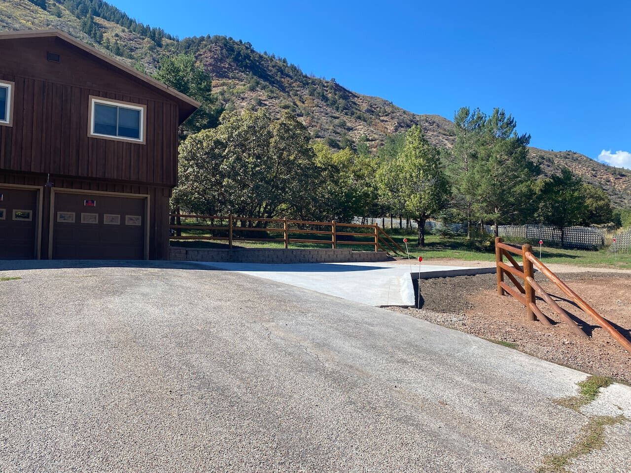 A gravel driveway leading to a wooden building with two garage doors.