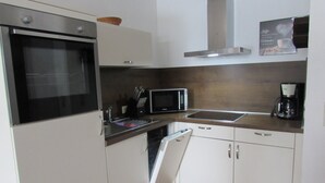 A compact kitchen with a built-in oven, microwave, sink, and dishwasher. - Vacation cottage in Hildfeld (Winterberg)