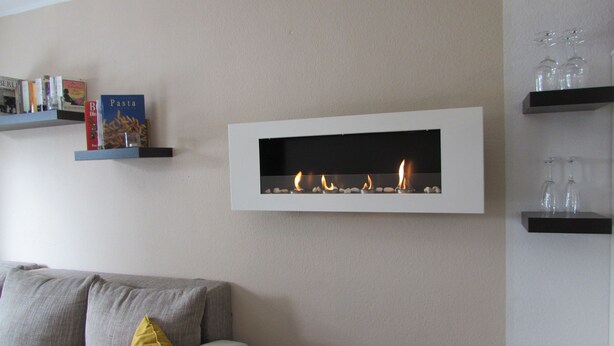 A modern living room with a built-in fireplace, a grey sofa with a yellow pillow, and bookshelves with various items. - Vacation cottage in Hildfeld (Winterberg)