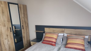 A bedroom with a bed, nightstands, a wardrobe, and a mirror. - Vacation cottage in Hildfeld (Winterberg)