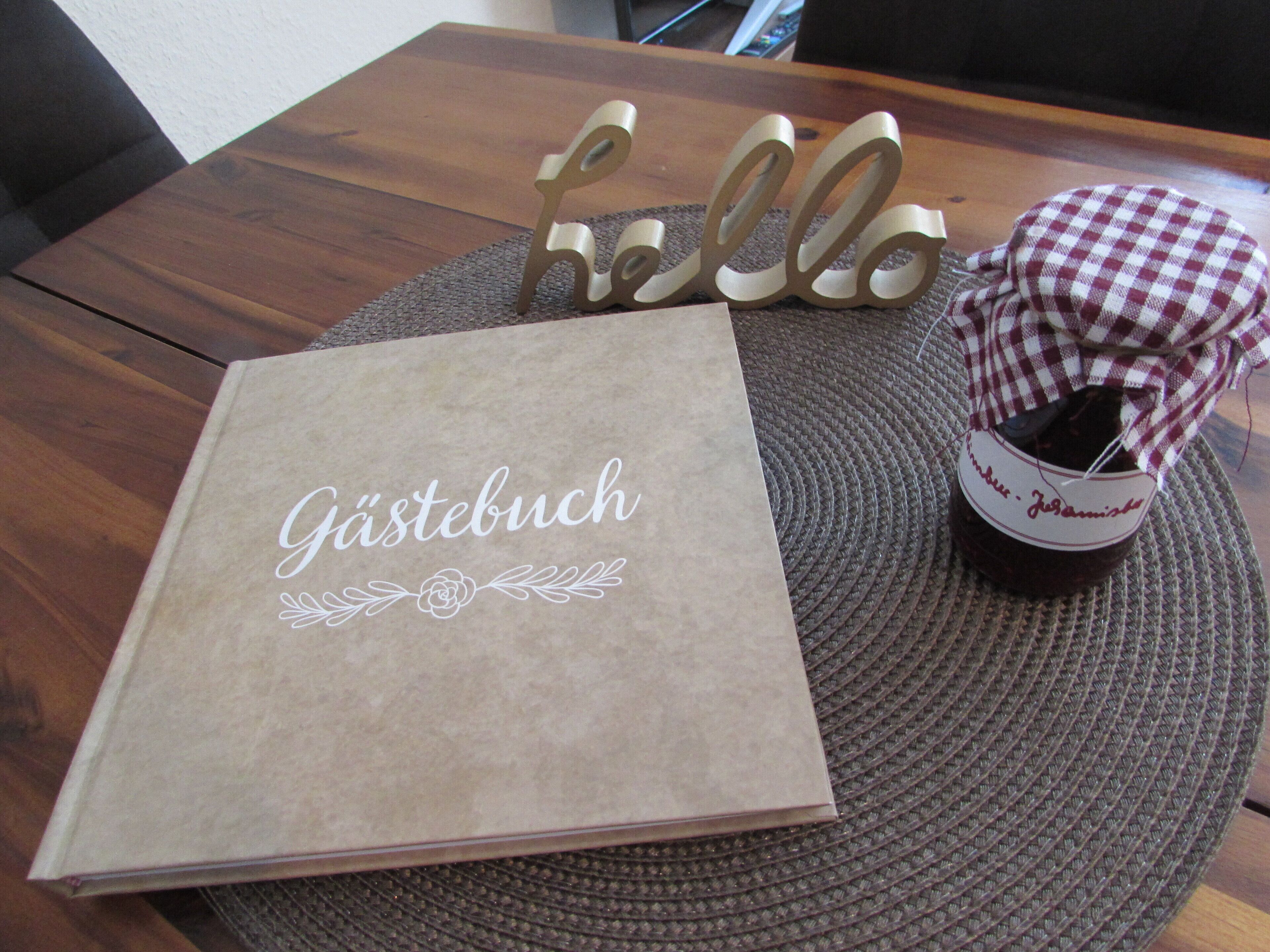 A table with a brown book titled 'Gästebuch' and a wicker basket with a checkered cloth.