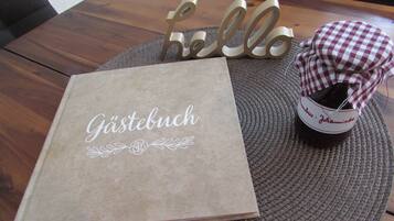 A table with a brown book titled 'Gästebuch' and a wicker basket with a checkered cloth.